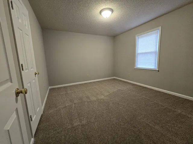 a view of an empty room with closet and wooden floor