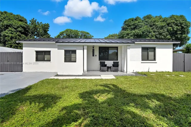 a front view of house with yard and trees in the background