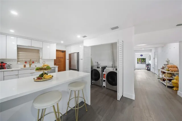 a kitchen with stainless steel appliances wooden floors and white cabinets