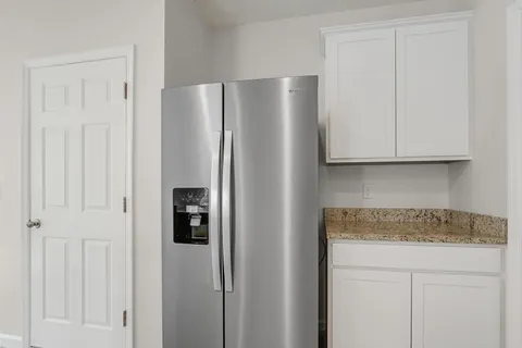 a kitchen with stainless steel appliances granite countertop white cabinets and a refrigerator