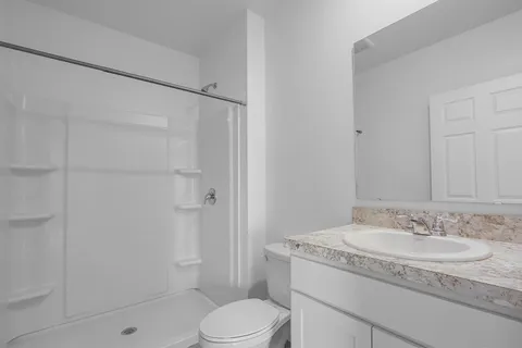a bathroom with a granite countertop sink a toilet and shower
