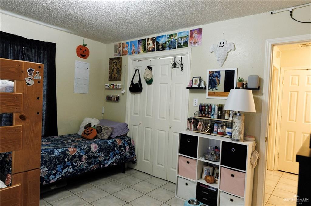 808 West Starr Avenue Pharr, TX 78577 - Photo 11 of 18 Bedroom featuring light tile patterned flooring, a textured ceiling, and a closet