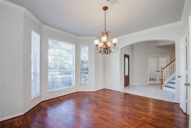 a view of an empty room with wooden floor and a ceiling fan
