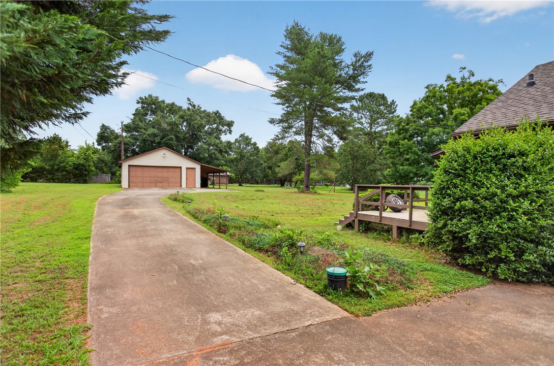 112 Holliday Lane Pendleton, SC 29670 - Photo 42 of 42 A long concrete driveway leads to a detached garage, offering ample outdoor space and mature trees.