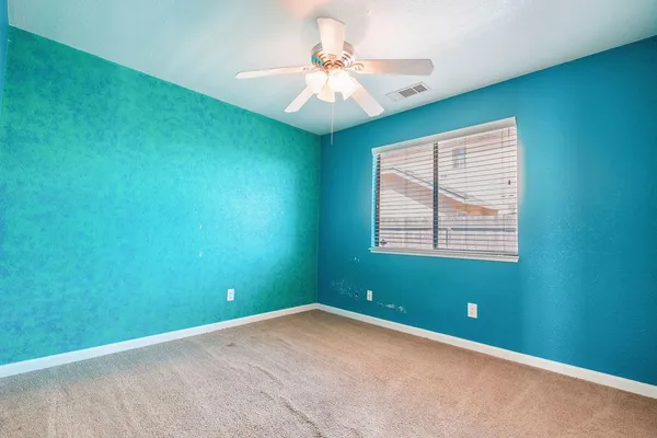 an empty room with a window and a chandelier fan