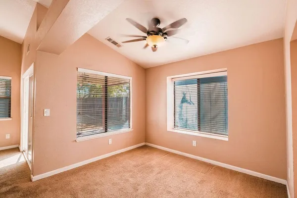 an empty room with windows and ceiling fan
