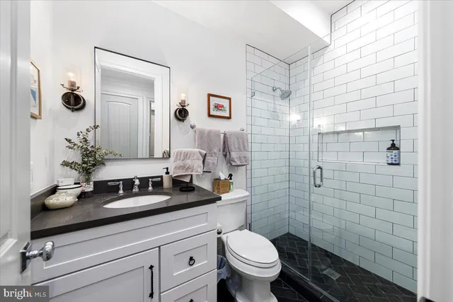 a bathroom with a granite countertop sink mirror vanity and toilet