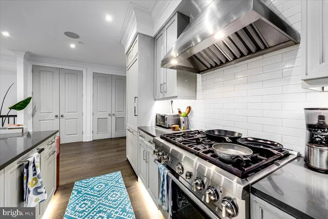 a kitchen with stainless steel appliances granite countertop a stove and a wooden floors