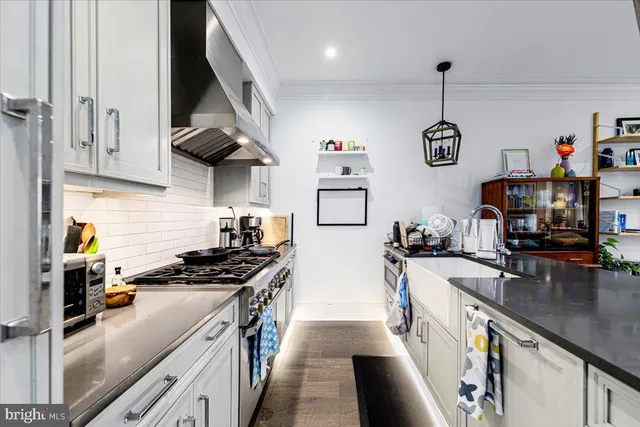 a kitchen with stainless steel appliances granite countertop a stove top oven a sink a counter space and cabinets