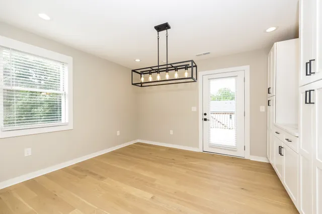 a view of a room with cabinet a chandelier and wooden floor