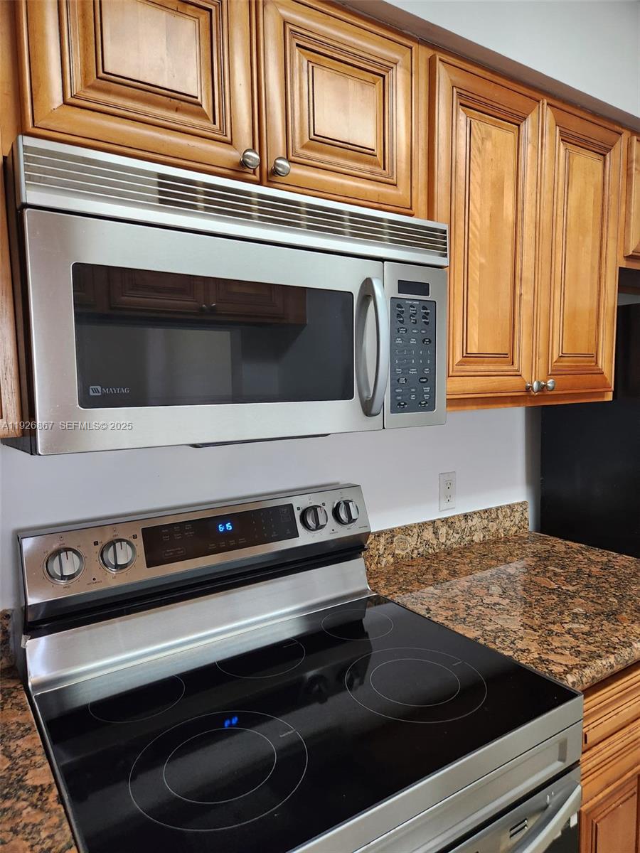 12124 St Andrews Place, Unit 206 Miramar, FL 33025 - Photo 3 of 20 a kitchen with wooden cabinets and a stove top oven