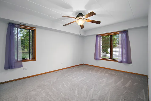 an empty room with windows and fan