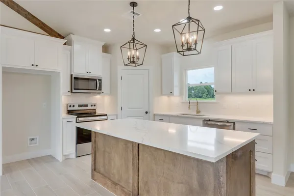 a large kitchen with stainless steel appliances granite countertop a sink a stove and a wooden floor