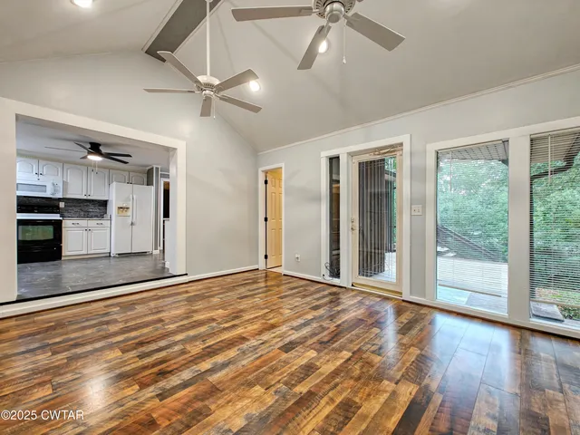 a view of an empty room with a window and wooden floor