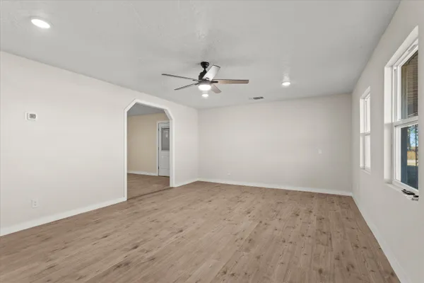 an empty room with wooden floor and ceiling fan