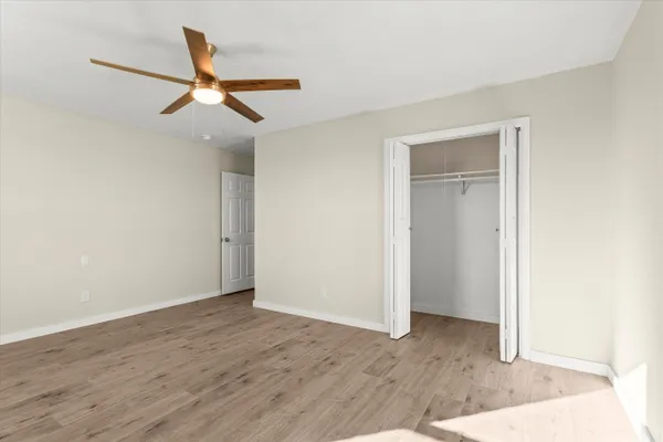 an empty room with wooden floor ceiling fan and windows