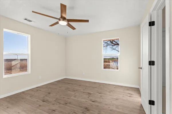 an empty room with a window and ceiling fan