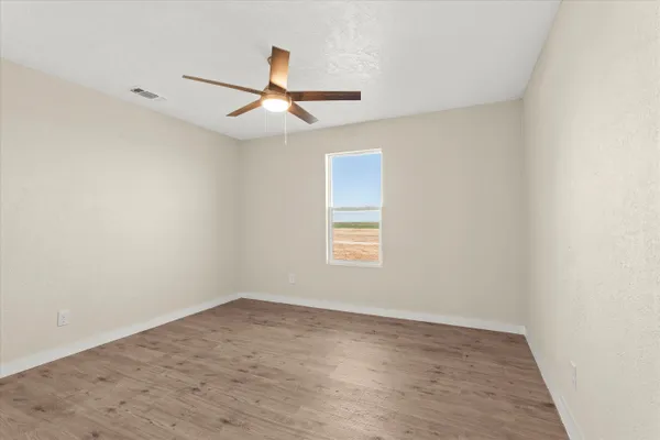 an empty room with a window and a ceiling fan