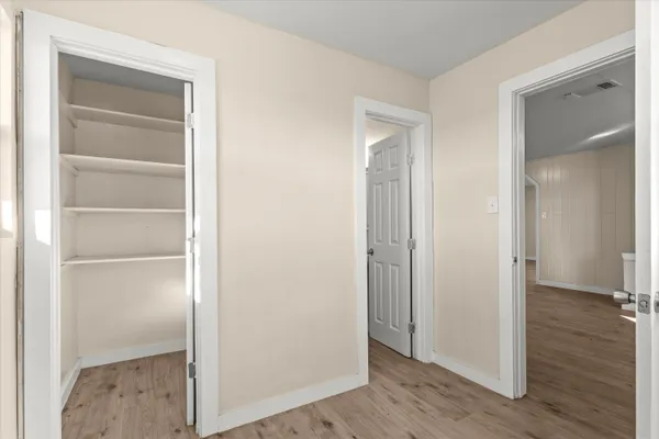 a view of an empty room with wooden floor & closet