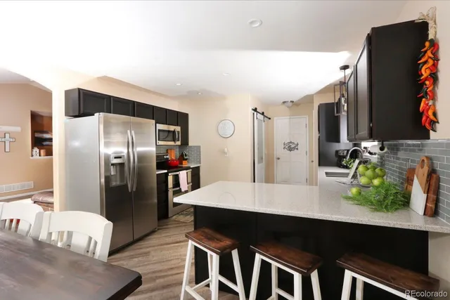 a kitchen with stainless steel appliances kitchen island granite countertop a refrigerator a stove and a sink
