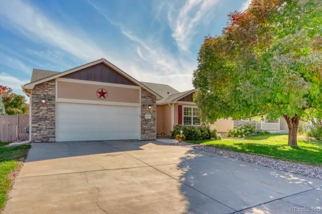front view of a house with a yard and a large tree