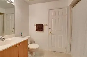 a bathroom with a granite countertop toilet sink and a mirror