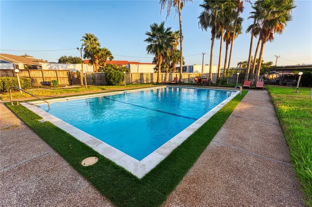 a view of a swimming pool with a chair and palm trees