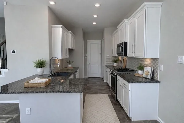 a kitchen with granite countertop stainless steel appliances a sink a stove top oven a counter space and cabinets