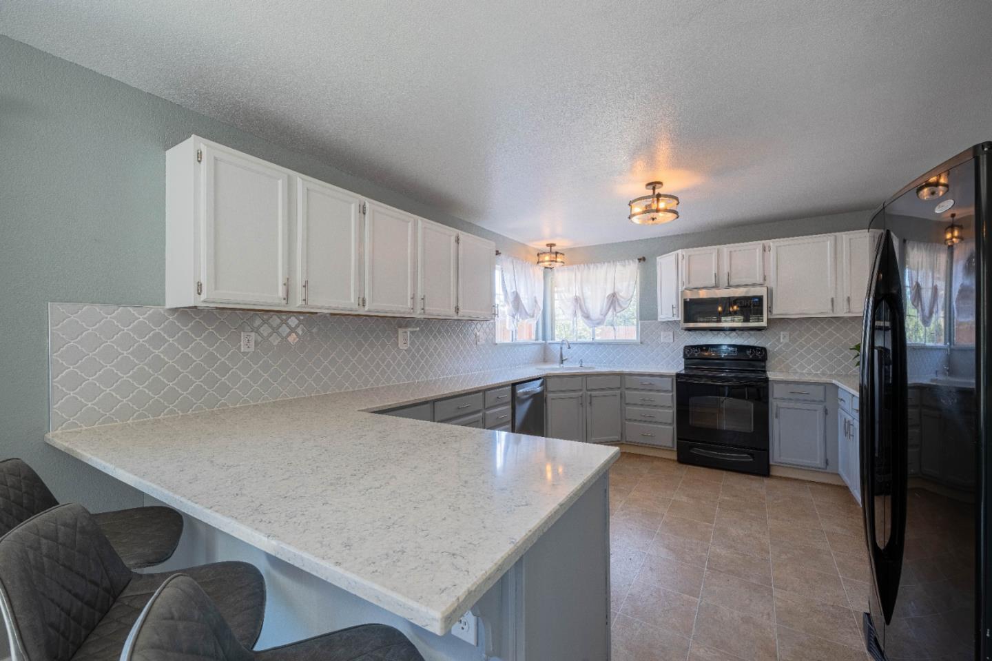 143 Tucker Road Watsonville, CA 95076 - Photo 14 of 42 a kitchen with granite countertop a refrigerator oven a sink dishwasher and white cabinets with wooden floor