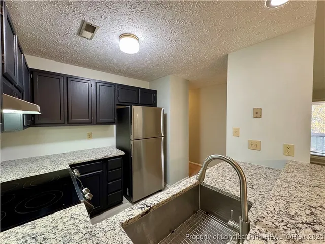 a kitchen with granite countertop stainless steel appliances a sink stove top oven and cabinets