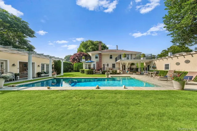 a view of pool with lawn chairs and large trees
