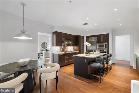 a kitchen with stainless steel appliances wooden floor dining table and chairs