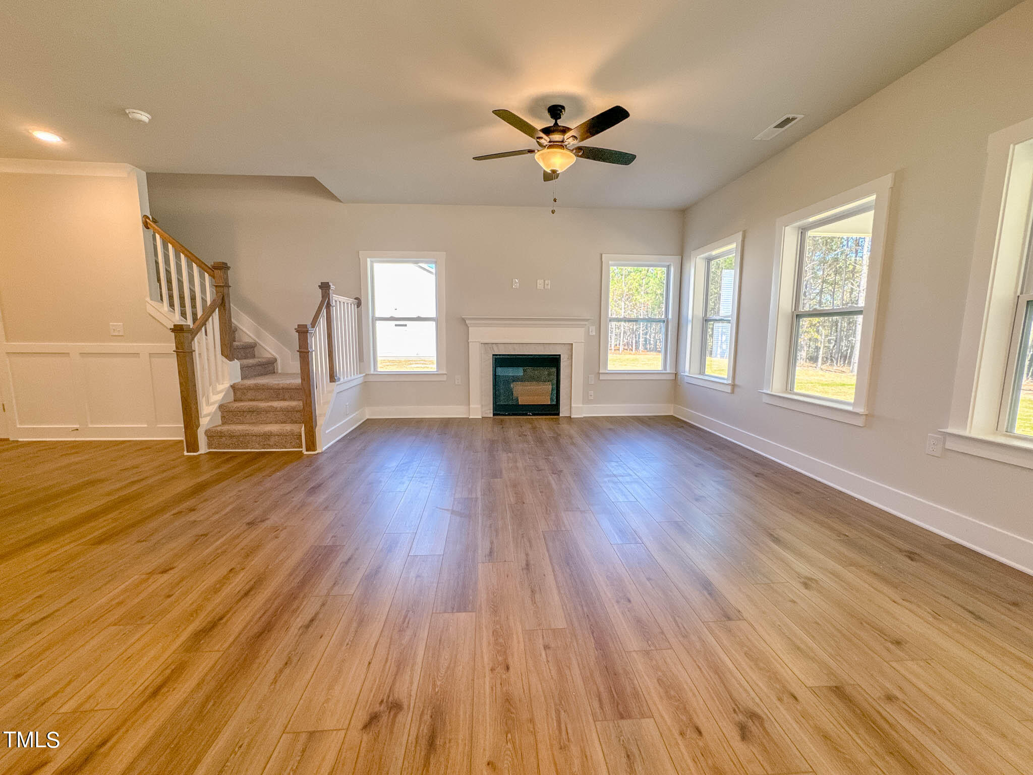 47 Beacon Hl Road, Unit SMITHFIELD Lillington, NC 27546 - Photo 25 of 69 a view of a livingroom with wooden floor a ceiling fan and windows