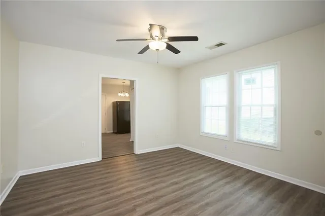 an empty room with wooden floor chandelier and windows