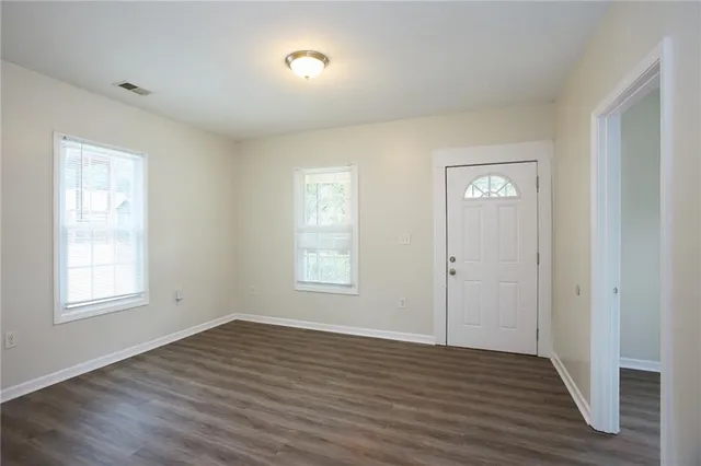 an empty room with wooden floor and windows