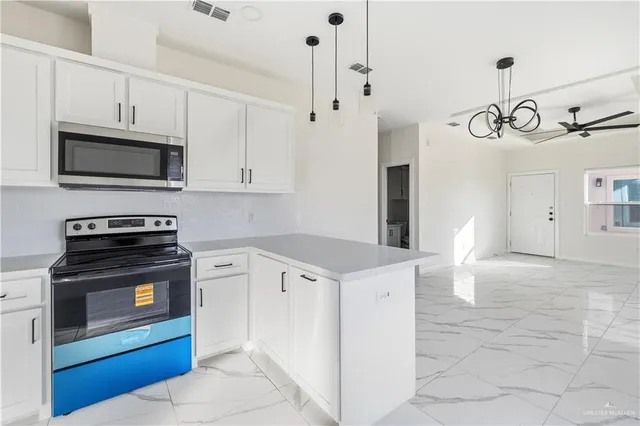 a kitchen with stainless steel appliances a stove a microwave and white cabinets