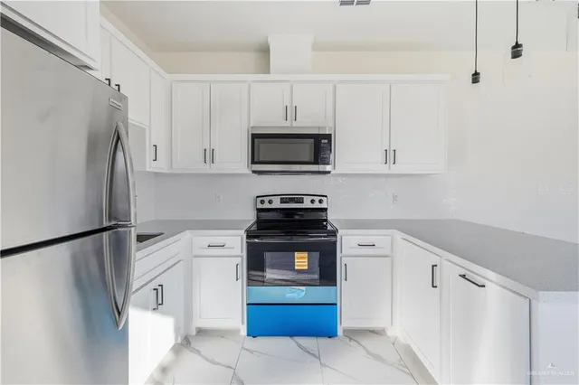 a kitchen with stainless steel appliances white cabinets and a refrigerator