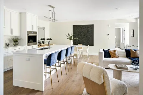 a living room with furniture a wooden floor and a kitchen view