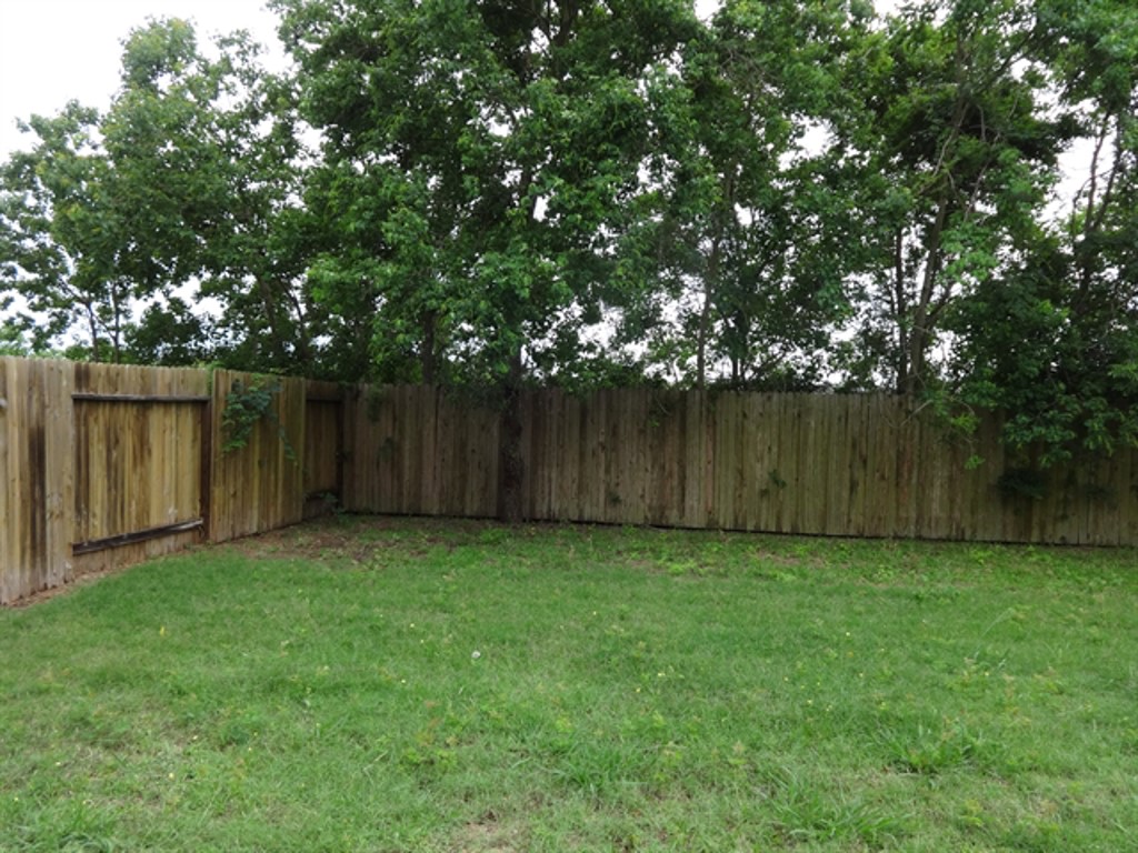 5318 Rio Drive Baytown, TX 77521 - Photo 10 of 11 a view of a backyard with large trees and wooden fence
