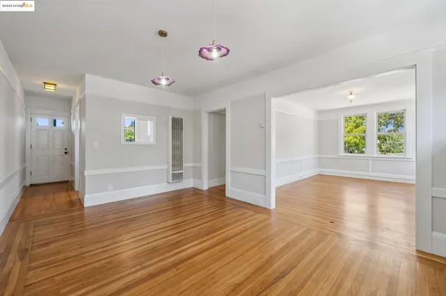 a view of an empty room with window and wooden floor
