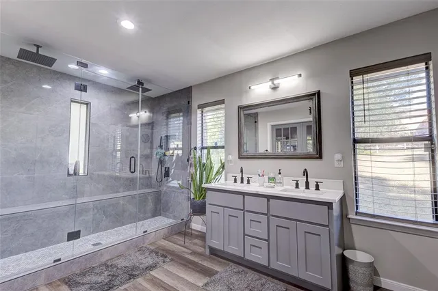 a spacious bathroom with double vanity sink a mirror and a shower