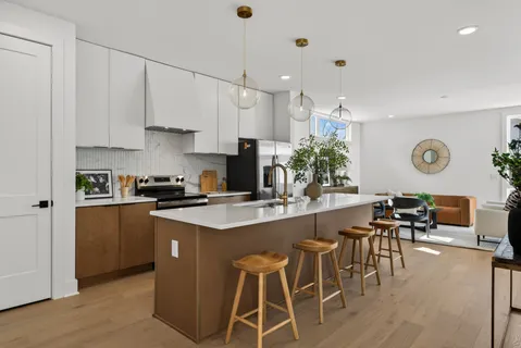 a kitchen with stainless steel appliances kitchen island granite countertop a stove a sink a dining table and chairs with wooden floor