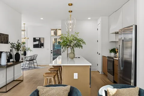 a kitchen with stainless steel appliances granite countertop a refrigerator a stove a sink a dining table and chairs