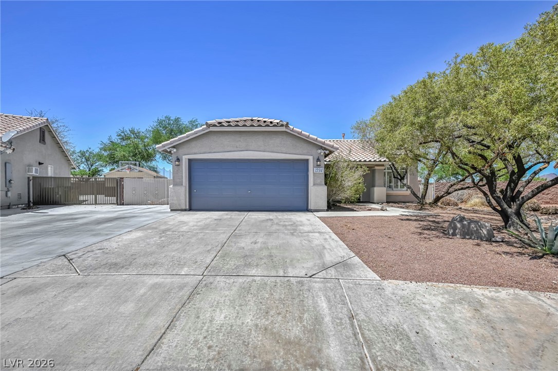 1234 Sunfire Street Henderson, NV 89014 - Photo 2 of 40 A well-maintained concrete driveway leads to a charming desert home with a tiled roof.