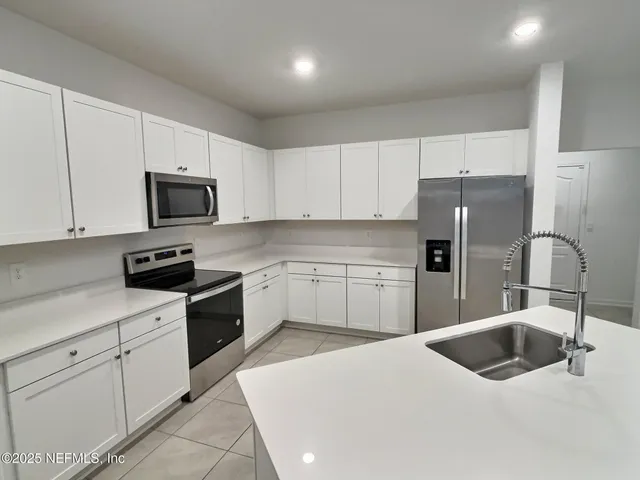 a kitchen with a sink white cabinets and stainless steel appliances