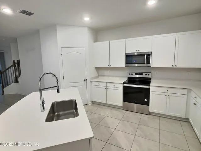 a kitchen with kitchen island granite countertop a stove a sink and a microwave
