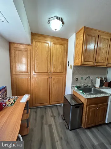 a room with kitchen island granite countertop wooden floors and a sink