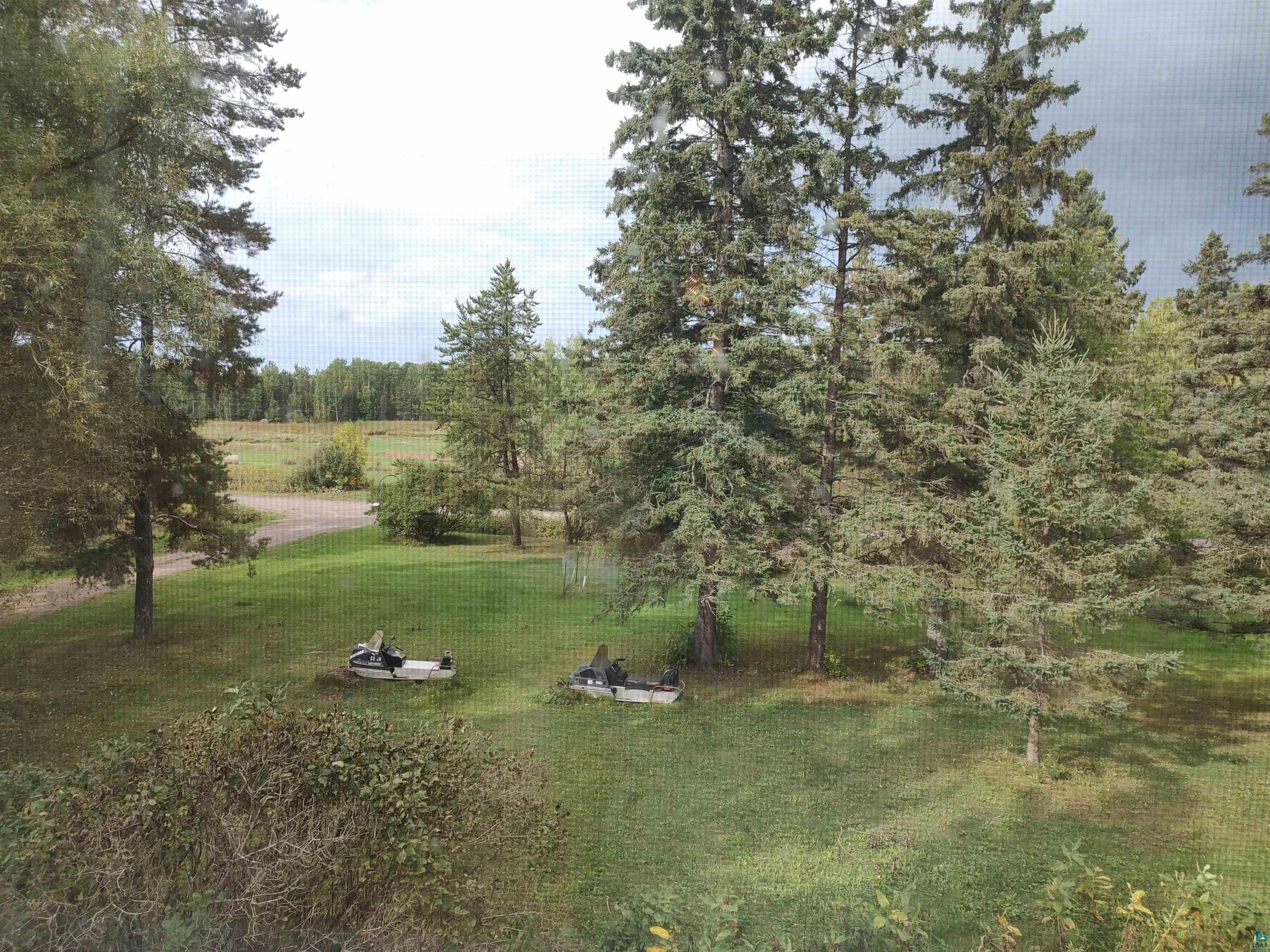 2585 Hautala Road Iron River, WI 54847 - Photo 20 of 28 Expansive outdoor grounds featuring mature evergreen and deciduous trees, a manicured lawn, and a distant field