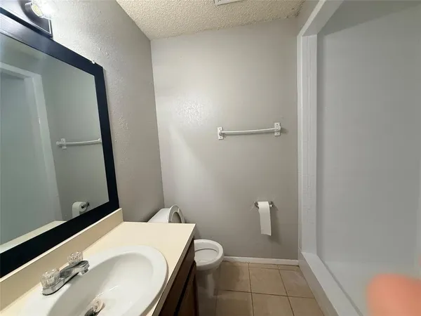 a bathroom with a granite countertop sink toilet and mirror