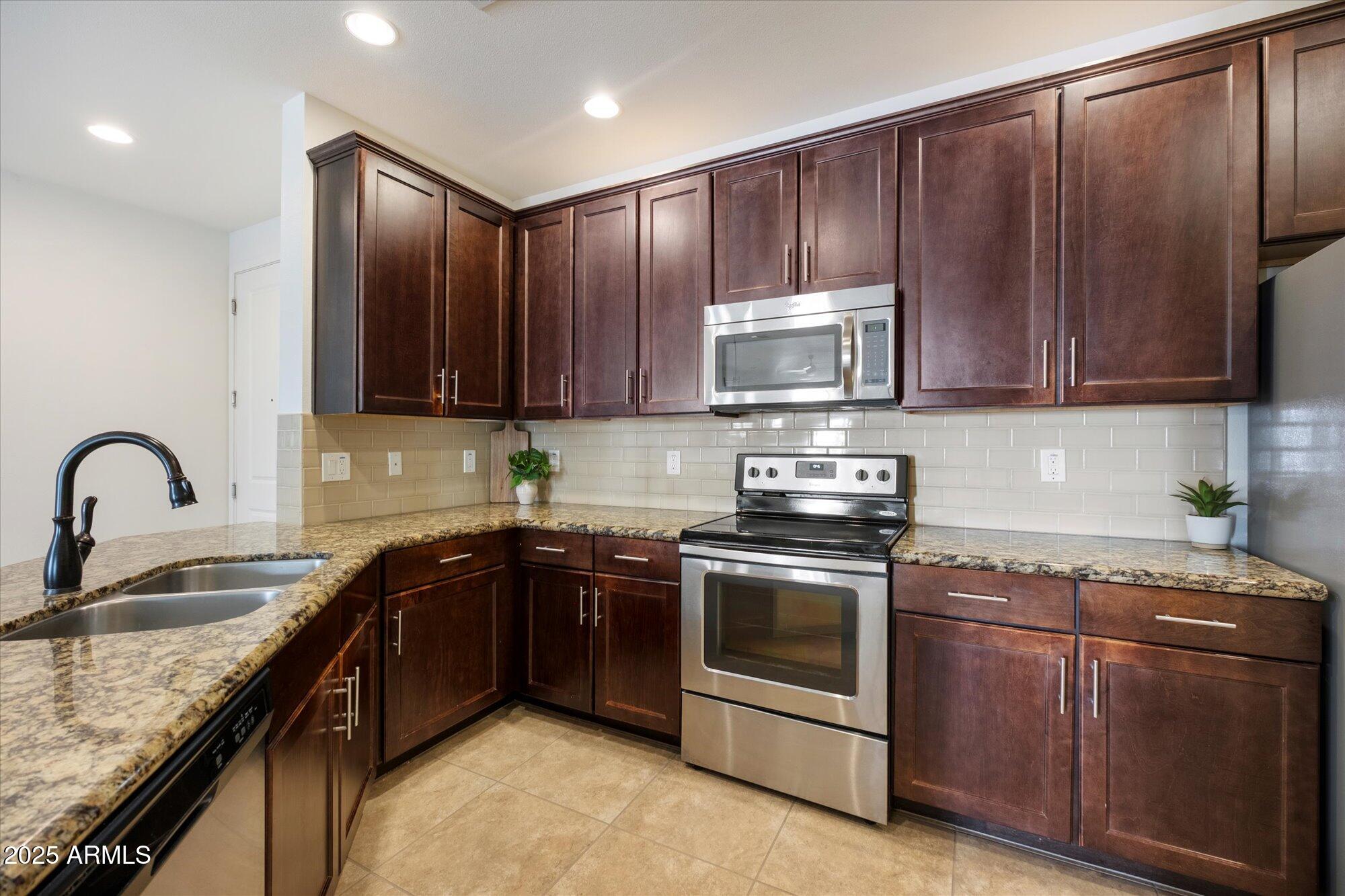 2511 West Queen Creek Road, Unit 230 Chandler, AZ 85248 - Photo 4 of 37 a kitchen with granite countertop wooden cabinets and stainless steel appliances
